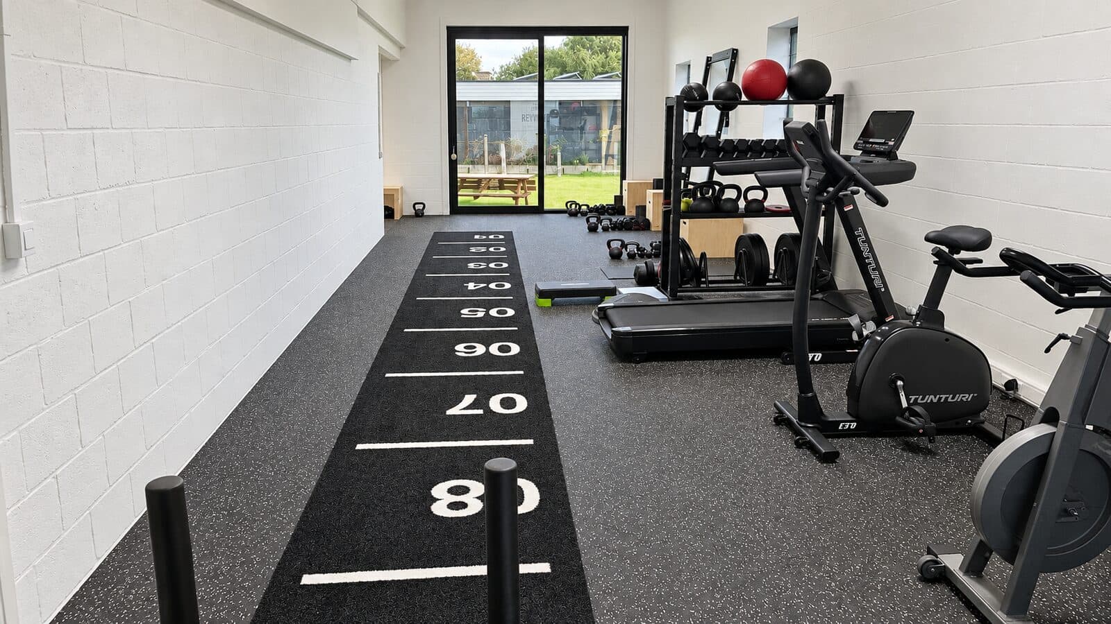 Loopband, fietsen en rek met kettlebells in de oefenzaal